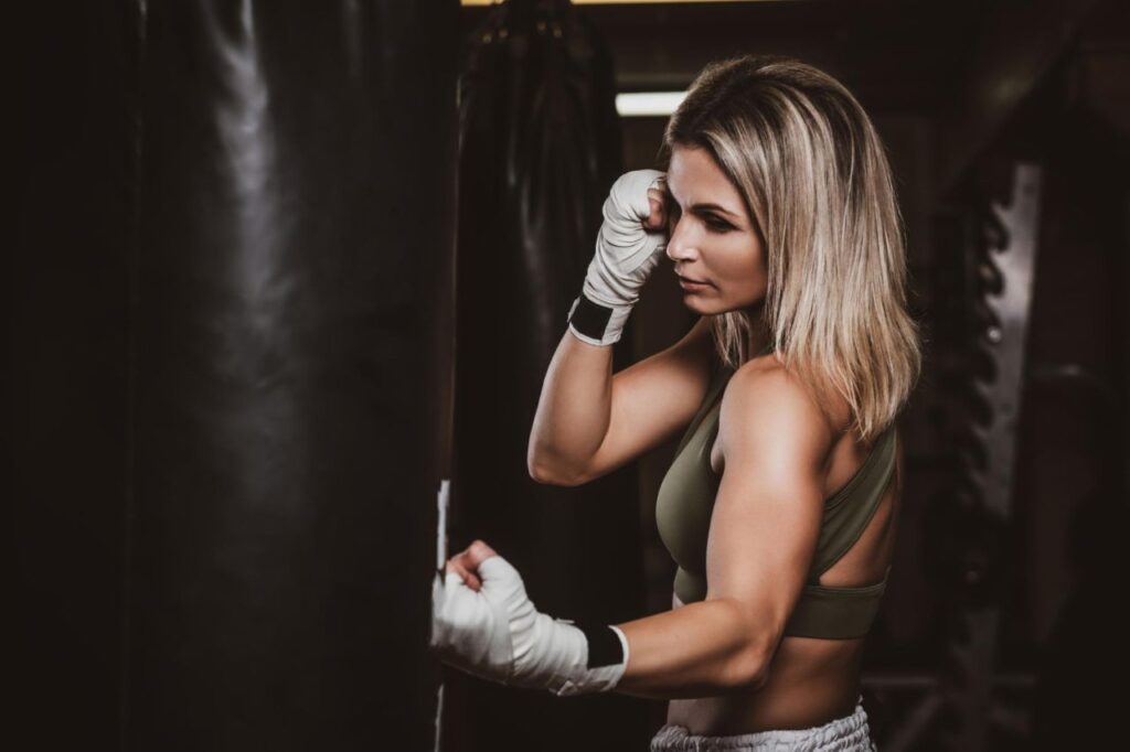 beautiful boxer female has her training with punching bag gym