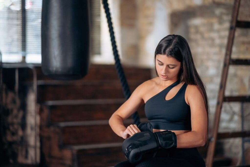 beautiful young fitness girl puts boxing glove